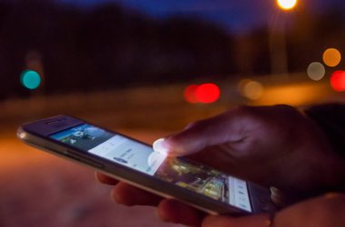 Kız ekranda akıllı telefonu işaret ediyor arka planda ışıklandırma gece atmosferik şehirde renk ışığı, hipster el ve cep telefonu kullanıyor, sim caddesini taklit ediyor, içerik yaşam tarzı