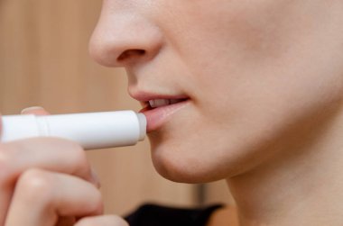 Çatlak ya da çatlamış, nemini kaybetmiş kuru dudaklar. Kadın dudaklarını koruyor. Dudak Bakımı.