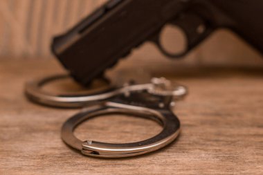 Ahşap arka planda kelepçeli siyah bir tabanca.