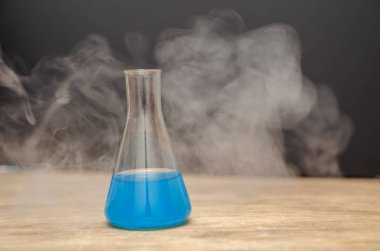 Siyah arka planda dumanla kaplı mavi bir şişe. kimyasal analiz