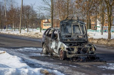 Güneşli bir kış gününde yolda yanmış bir araba.