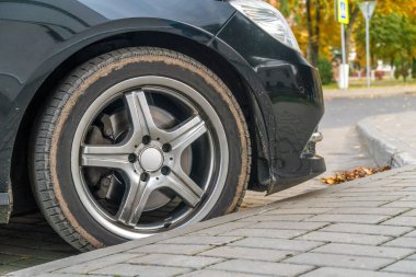 Sonbaharda park etmiş siyah bir arabanın yan görüntüsü.