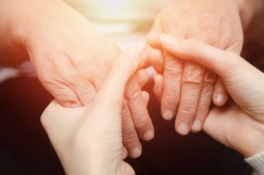 Yaşlı, yaşlı bir kadının elini tutan genç bir kızın elleri. İki kuşak kadın konsepti