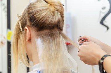 Kuaför saç boyamak için saç tellerini dağıtır.