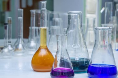 Masanın üzerinde çok renkli sıvı bulunan laboratuvar camları. Kimyasal analiz.