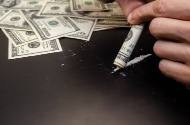 Erkek eller siyah bir arka planda bir dolar üzerinden uyuşturucu kokluyor.