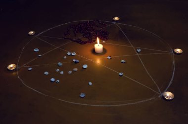 Pentagram yere boyanır, mumlar yakılır, boncuklar yerde yatar, kabuklar dağılır. Okült ve esrarengiz sembollerle büyü kavramı.