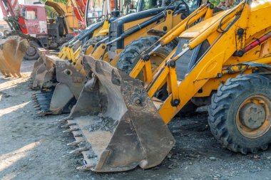 Güneşli havada peş peşe birkaç buldozer kovası.