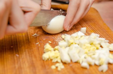 Kadın elleri tahta bir tahtada yumurta kesiyor. Yaklaş.