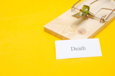 Üzerinde bir parça kağıt olan bir fare kapanı ve bir kopya alanı olan sarı bir arka planda ölüm yazısı. kavram veya fikir