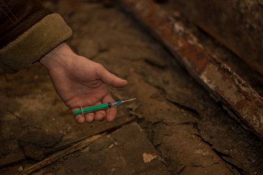 Uyuşturucu bağımlılığı temasına karşı, erkek ellerine uyuşturucu şırıngasıyla bakış, bodrumda, dünya uyuşturucu sorunu