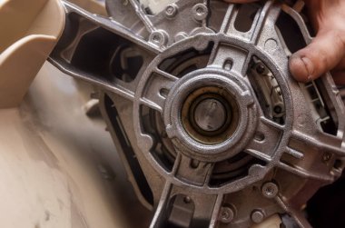 Bir çamaşır makinesini tamir eden teknisyen; yakın plan, motor