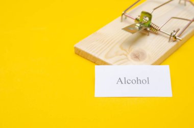 Fare kapanı, üzerinde bir parça kağıt ve sarı arka planda bir kopya alanı olan yazıtlı alkol. kavram veya fikir