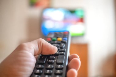 Uzaktan kumandalı bir adam televizyonu işaret ediyor. Uzaktan kumandalı ele odaklan.