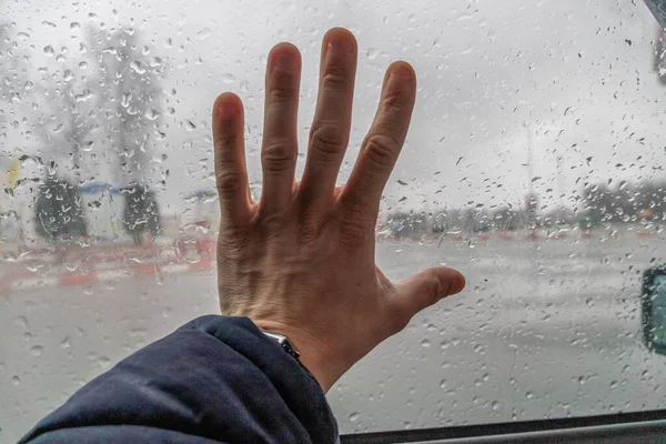 Rainy mood. Some person touching the glass while raining day.