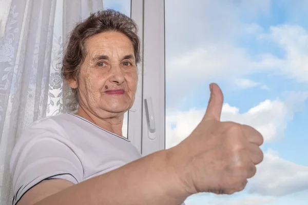 Starsza Ciemnowłosa Kobieta Podniesionym Palcem Prawej Ręki Tle Okna Niebieskim — Zdjęcie stockowe