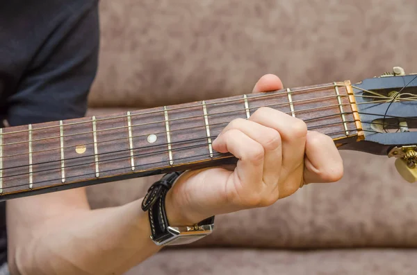 Close-up of a guitarist\'s hand on an acoustic guitar. Guitar player\'s hand on the fretboard of an acoustic guitar close-up