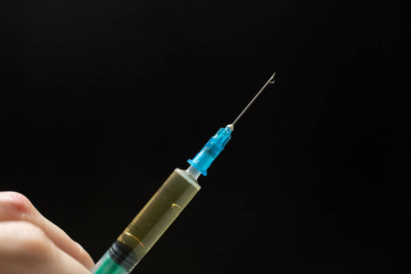Syringe with injection drops on a black background with a copy of the space