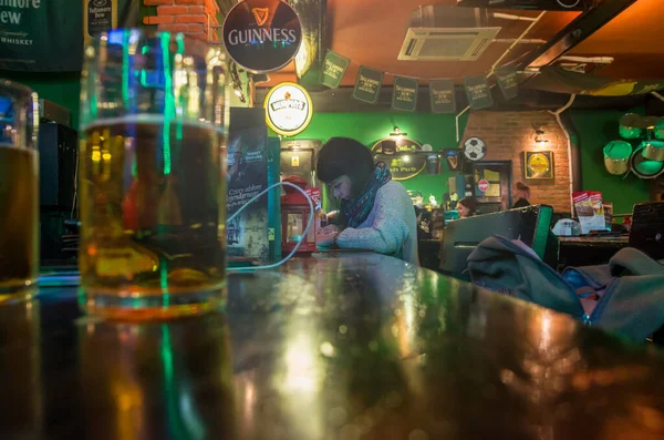 the woman sitting in the bar with smartphone at the bar