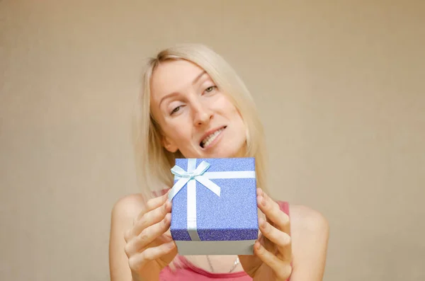 Ragazza Bionda Scherzi Smorfie Tiene Una Scatola Regalo Blu Lucido — Foto Stock