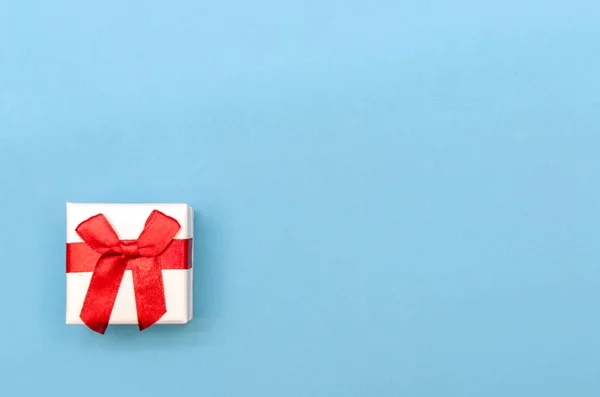 White box with red bow on blue background. Concept of Valentine's Day, wedding, birthday, New Year, Christmas and other holidays