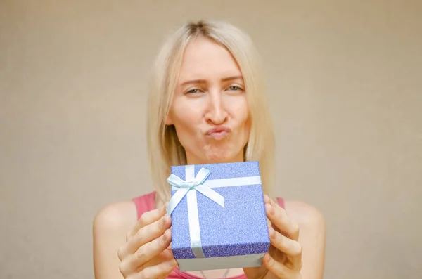 Ragazza Bionda Scherzi Smorfie Tiene Una Scatola Regalo Blu Lucido — Foto Stock