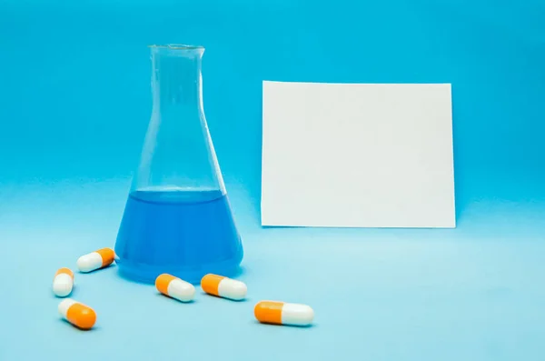 Flask Blue Liquid Orange White Capsules Blue Background Background White — Stock Photo, Image