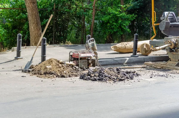 Professional tools for repairing asphalt road pit: shovel, hammer on the background of the city. Overhaul of the main street of the city, road construction; Tbilisi