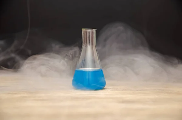 瓶中的蓝色液体在黑色背景的烟雾中 化学分析 — 图库照片