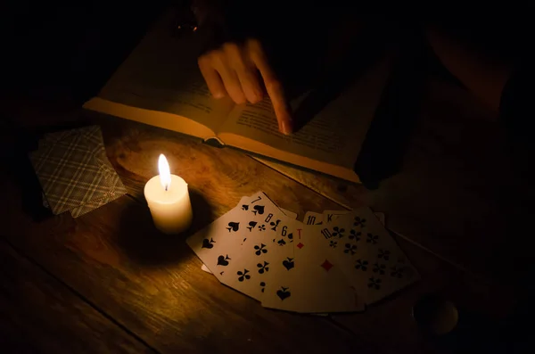 Cards, a book, a candle, a hand on a wooden table. study of magic. concept of divination, magic.