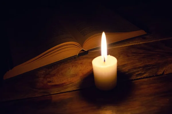 Tahta Bir Masanın Üzerinde Karanlıkta Yanan Bir Mum Bir Kitap — Stok fotoğraf