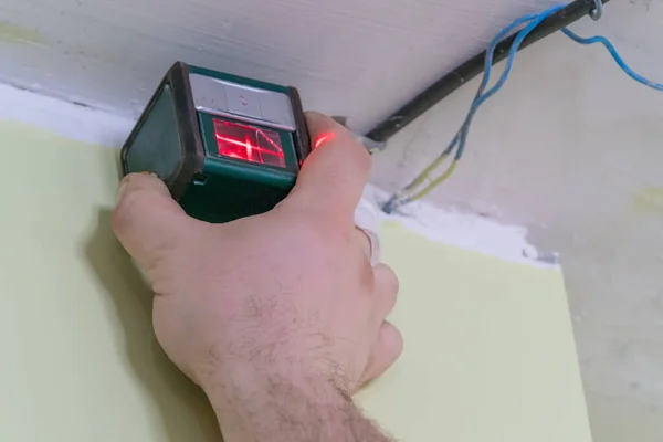 Marking the wall with a laser level for installation of a stretch ceiling. Red light on the wall. Repair and construction. — Stock Image Marking Wall Laser Level Installation Stretch Ceiling Red Light Wall Stock Image