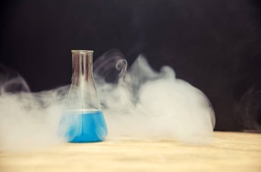 Siyah arka planda dumanla kaplı mavi bir şişe. kimyasal analiz