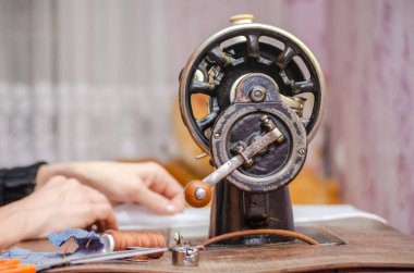 Eski bir dikiş makinesinde çalışan bir kadın. Eller yakın plan.