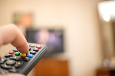 Uzaktan kumandalı bir adam televizyonu işaret ediyor. Uzaktan kumandalı ele odaklan.