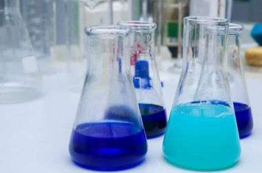 Masanın üzerinde çok renkli sıvı bulunan laboratuvar camları. Kimyasal analiz.