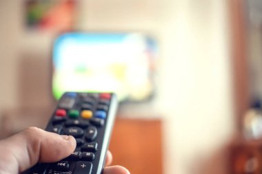 Uzaktan kumandalı bir adam televizyonu işaret ediyor. Uzaktan kumandalı ele odaklan.