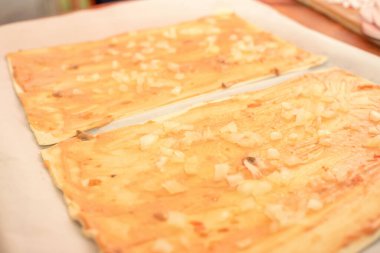 Pizzayı hazırlayan, dikdörtgen pizza tabanına sosis serpiştiren bir kadının yakın çekimi.