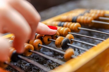 Kırmızı tırnak cilası olan bir kadının eli mermer bir masada duran ahşap banknotlara güvenir.