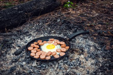 Yumurta ve sosisler ormanda kömürde tavada kızartılır. Doğada kahvaltı, piknik..