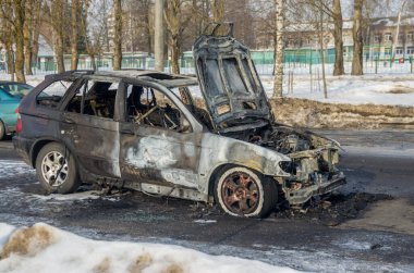Güneşli bir kış gününde yolda yanmış bir araba.