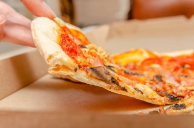 Kadın eli, basit bir karton kutudan mantarlı et pizzası alır.