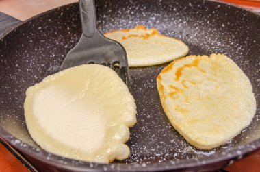 Siyah bir tavada üç krep kızartılıyor. Kahvaltı konsepti.