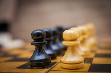 Siyah ve beyaz piyonlar satranç tahtasında birbirlerinin önünde.