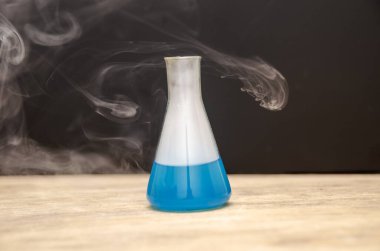 Siyah arka planda dumanla kaplı mavi bir şişe. kimyasal analiz