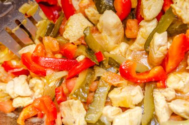 Kazanda kızarmış tavuk eti, kırmızı çan biberi, domates, turşu, beyaz soğan