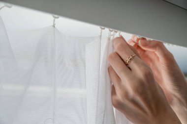 Kadın kapalı ya da kapalı, kapalı beyaz perdeleri kaldırır.