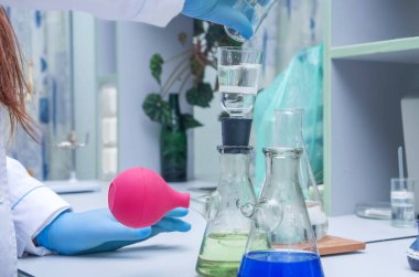 Bir kimyager elinde cam bir test tüpü tutar, sıvı çözeltiyi taşır, çeşitli reaksiyonlar kullanarak kimyasal reaktör seçenekleri kullanır..