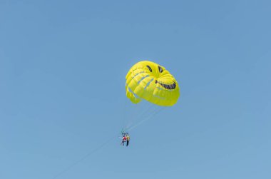 Paraşütlü adam için sarı bir paraşüt açık mor gökyüzünün arka planında havada uçuyor.