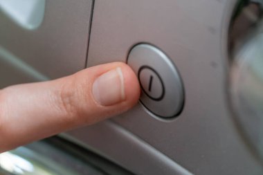 Kadının parmağı çamaşır makinesini çalıştırmak için düğmeye basar. Kapat.